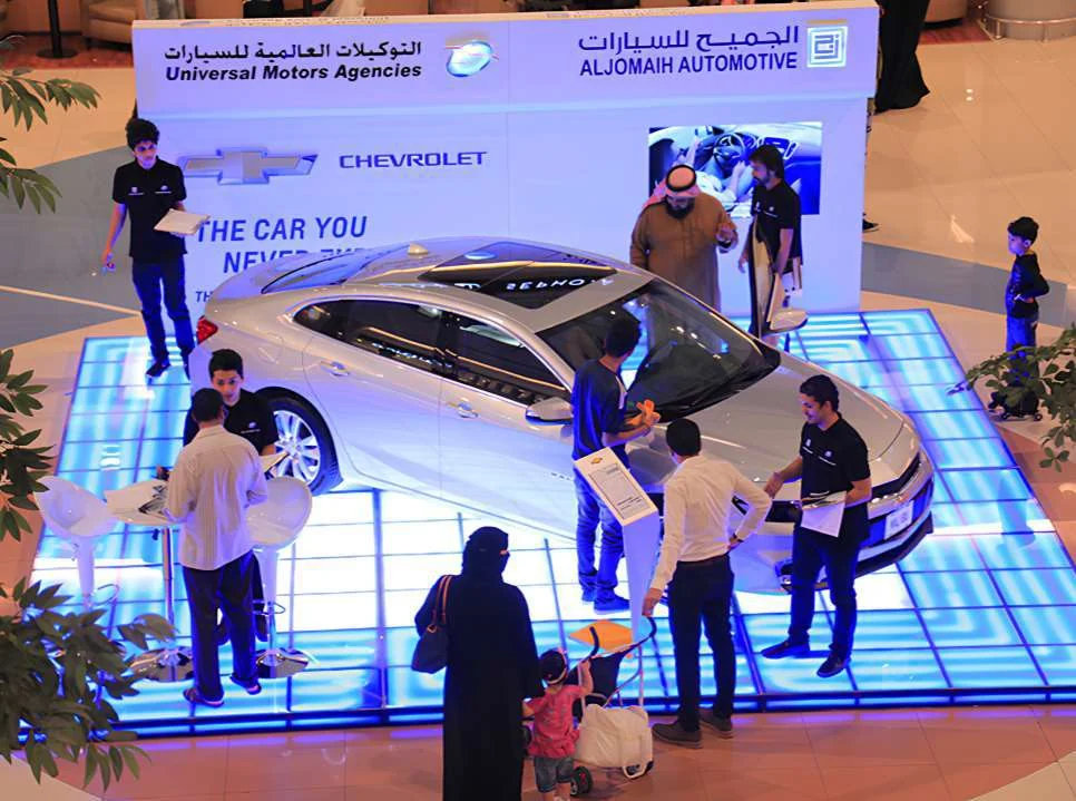 Chevrolet Malibu on an illuminated blue activation platform with visitors and on-site staff